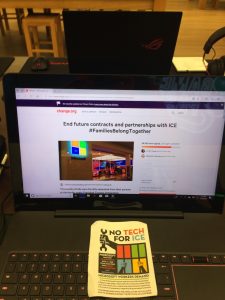 Laptop in Microsoft Store displaying change.org petition, with flyer on keyboard