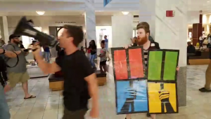 Two DSA members in Lenox hall, holding a megaphone and a modified MS Windows logo with a superimposed cage